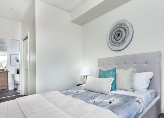 A bedroom with a large bed and a round decorative piece on the wall.