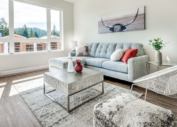 A living room with a grey sofa, a glass coffee table, and a white chair.