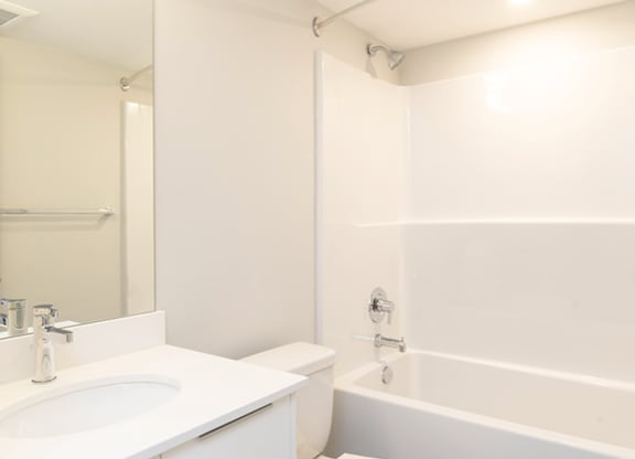 A white bathroom with a toilet, sink, and bathtub.