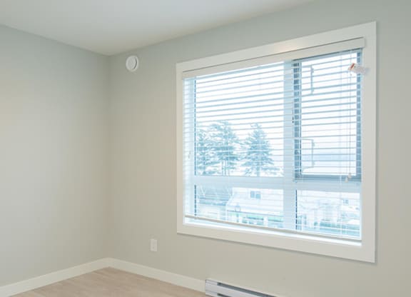 A room with a window showing a view of a residential area.