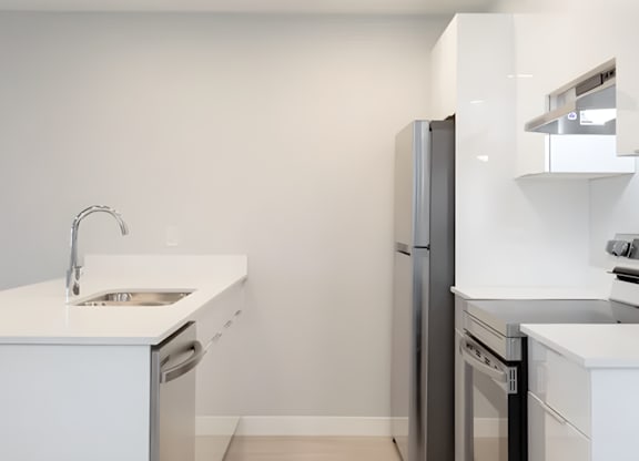 A modern kitchen with a white countertop and stainless steel appliances.