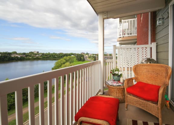 A balcony with a chair and a table with a view of a river.