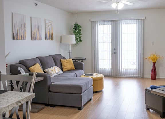 A living room with a grey couch and a yellow ottoman.