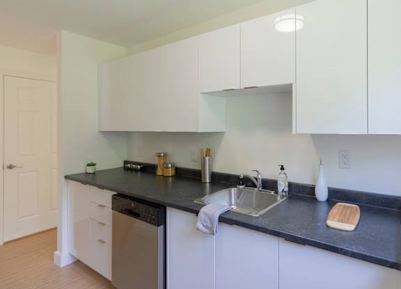 A kitchen with white cabinets and black countertops.