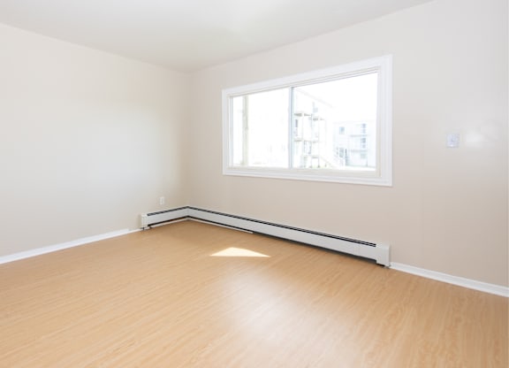 Empty room with a window and a radiator on the wall.