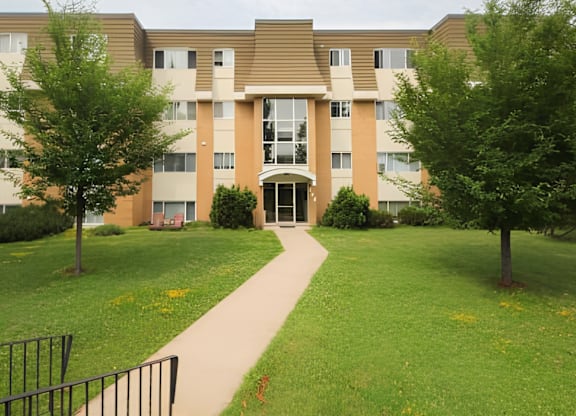 A building with a brown roof and tan walls with a walkway in front.