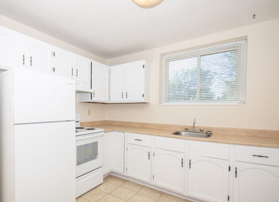A kitchen with white cabinets and appliances.