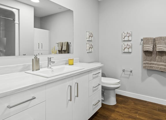 A white bathroom with a toilet, sink, and mirror.