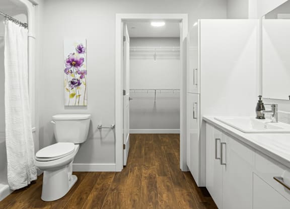 A white toilet sits in a bathroom with a white sink and a white cabinet.