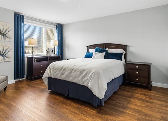 A bedroom with a large bed and a wooden floor.
