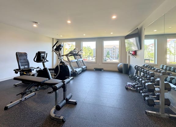 A spacious gym with a variety of equipment including treadmills, stationary bikes, and weight machines.