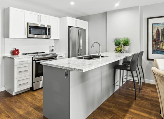 A modern kitchen with a marble countertop and stainless steel appliances.