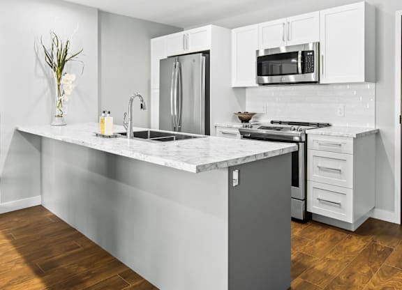A modern kitchen with a marble countertop and stainless steel appliances.