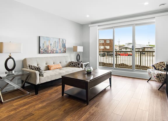 A modern living room with a sofa, coffee table, and a view of the outside.