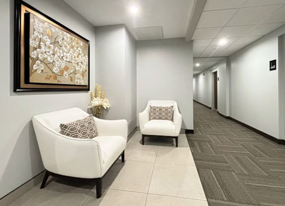 A hallway with two chairs and a painting on the wall.