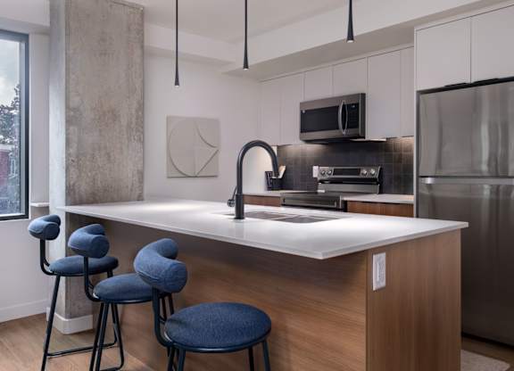 A modern kitchen with a bar area and blue stools.