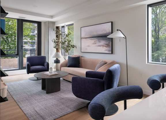 A living room with a grey rug and a large painting on the wall.