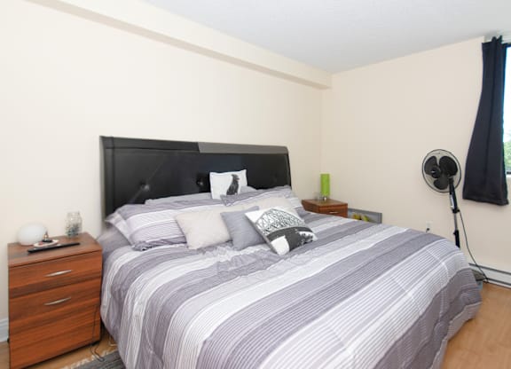 A bedroom with a bed, nightstand, and lamp.