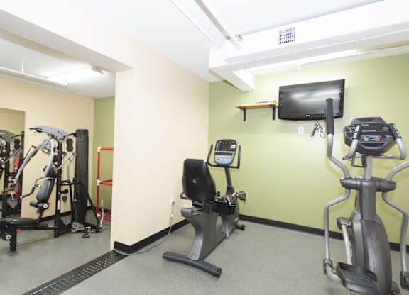 A gym with a treadmill, exercise bike, and a television.