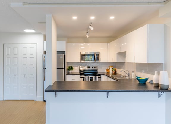 A modern kitchen with a black countertop and white cabinets.