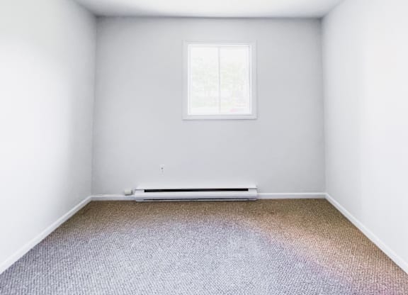 A room with a window and a radiator on the floor.