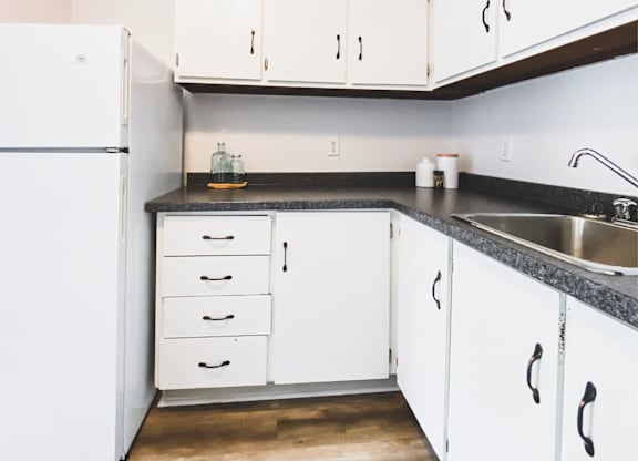 A kitchen with white cabinets and a black countertop.