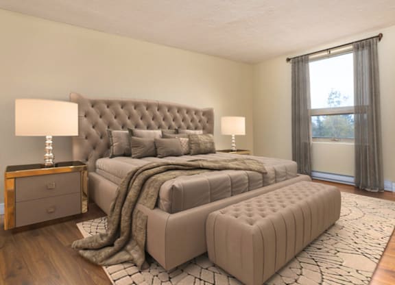 A bedroom with a large bed and a window with curtains.