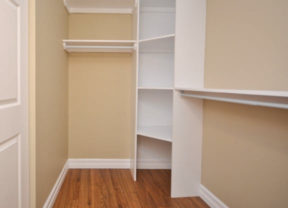 A white shelving unit in a room with beige walls and wooden floors.