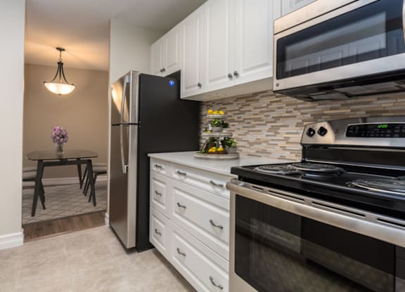 A kitchen with black appliances and white cabinets.