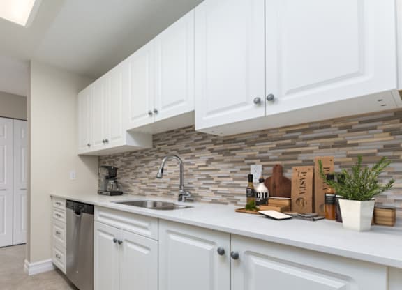 A kitchen with white cabinets and a stone backsplash.