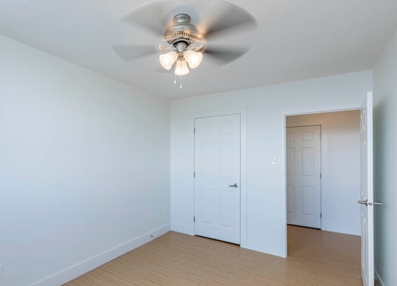 A room with a ceiling fan and two doors.
