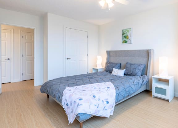 A bedroom with a bed, a ceiling fan, and a nightstand.