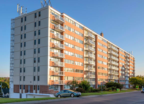 A large apartment building with a car parked in front.