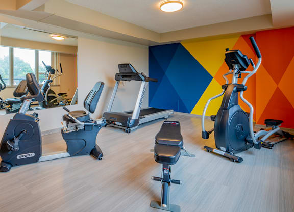 A gym with a row of exercise bikes and elliptical machines.