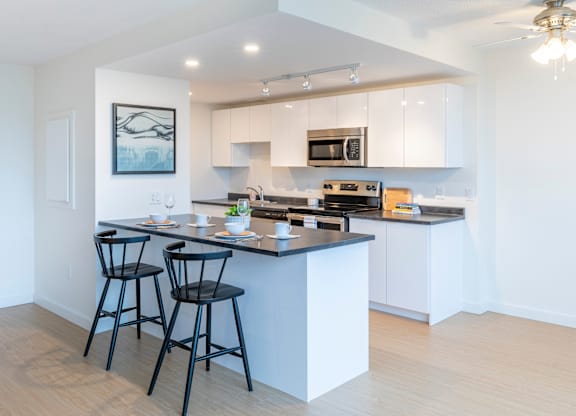 A kitchen with a bar area and two black chairs.