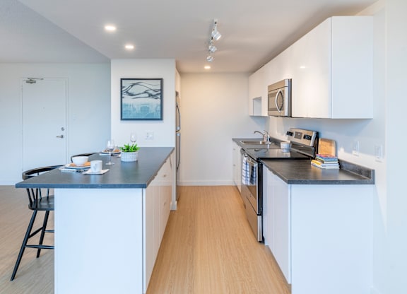 A kitchen with white cabinets and a black countertop.