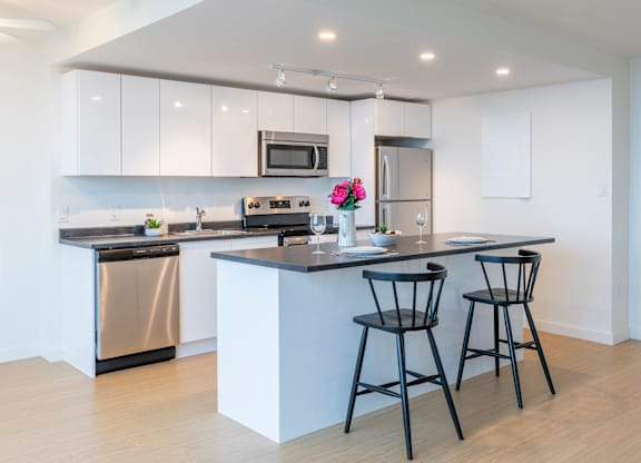 A modern kitchen with a black countertop and white cabinets.