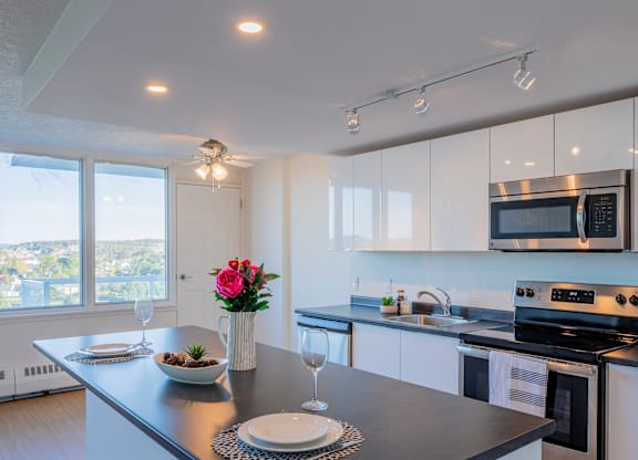 A modern kitchen with a black countertop and white cabinets.