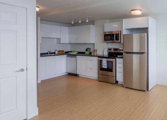 A kitchen with white cabinets and a wooden floor.