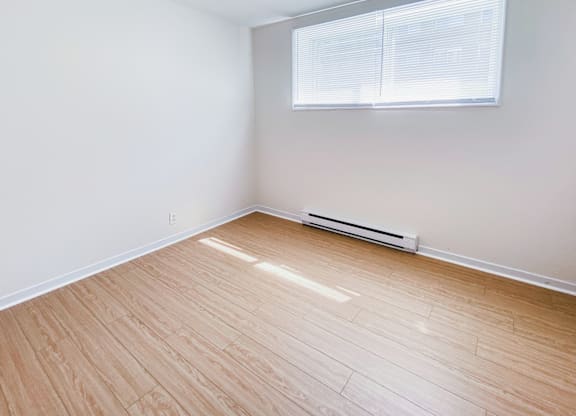 A room with a window and a radiator on the floor.