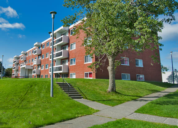 A red brick apartment building with a tree in front.