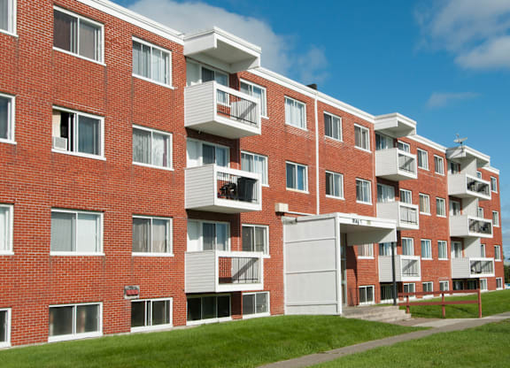 A red brick apartment building with white balconies and doors.