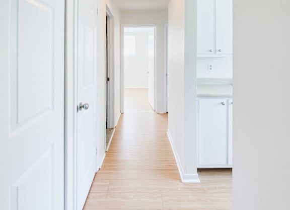 A long hallway with white doors and cabinets.