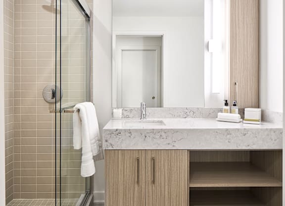 A white towel hangs on a glass shower door in a modern bathroom.