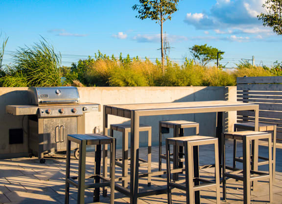 A set of outdoor bar stools are in front of a concrete counter.