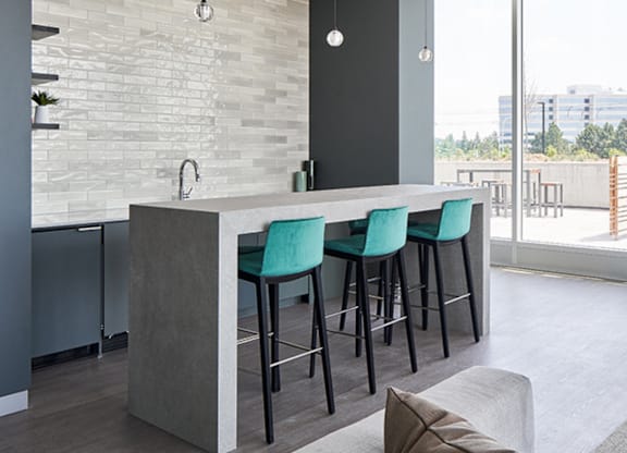 A modern kitchen with a bar area and green chairs.