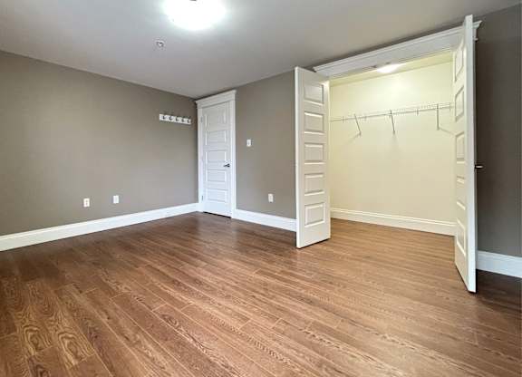 A room with a white closet and wooden floors.