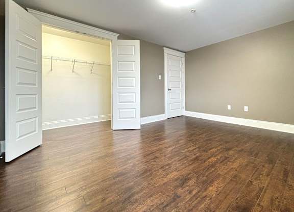 A room with a white door and a wooden floor.