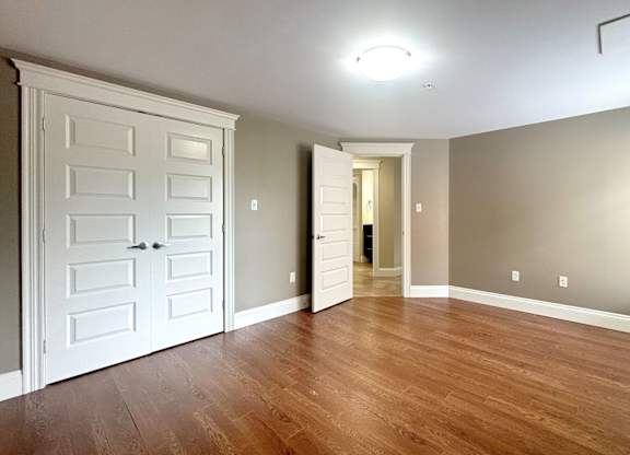 A room with a white door and wooden flooring.