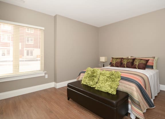 A bedroom with a bed, a bench, and a window.